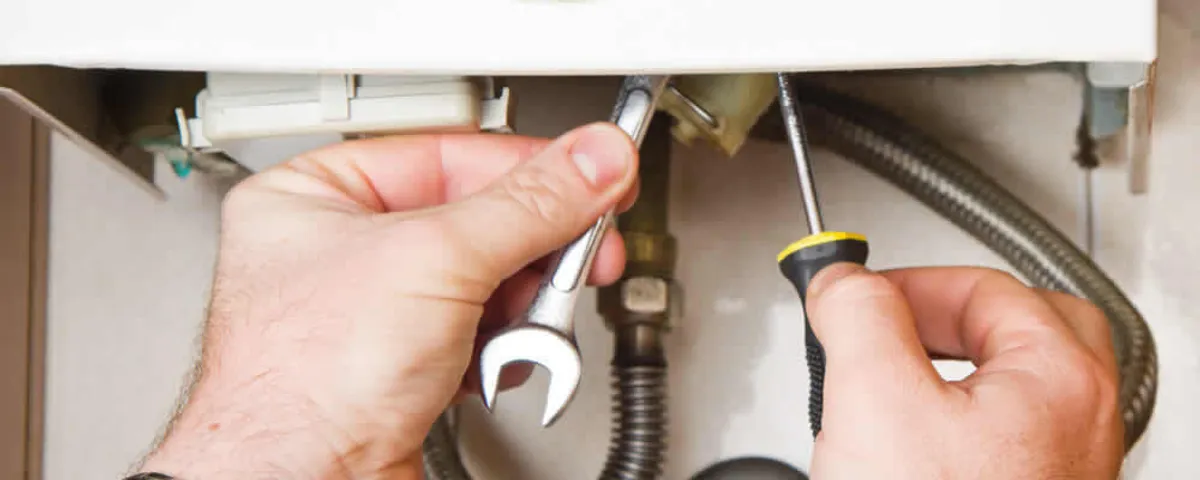 Boiler repair technician tightening pipe fittings and connections in Concord, MA