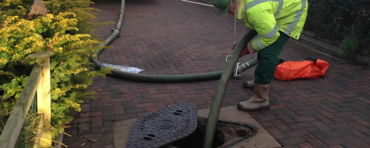 Septic tank cleaning technician servicing a septic tank with a vacuum hose in Concord, MA