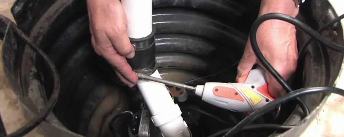 Sump pump installation technician connecting PVC discharge piping in Concord, MA